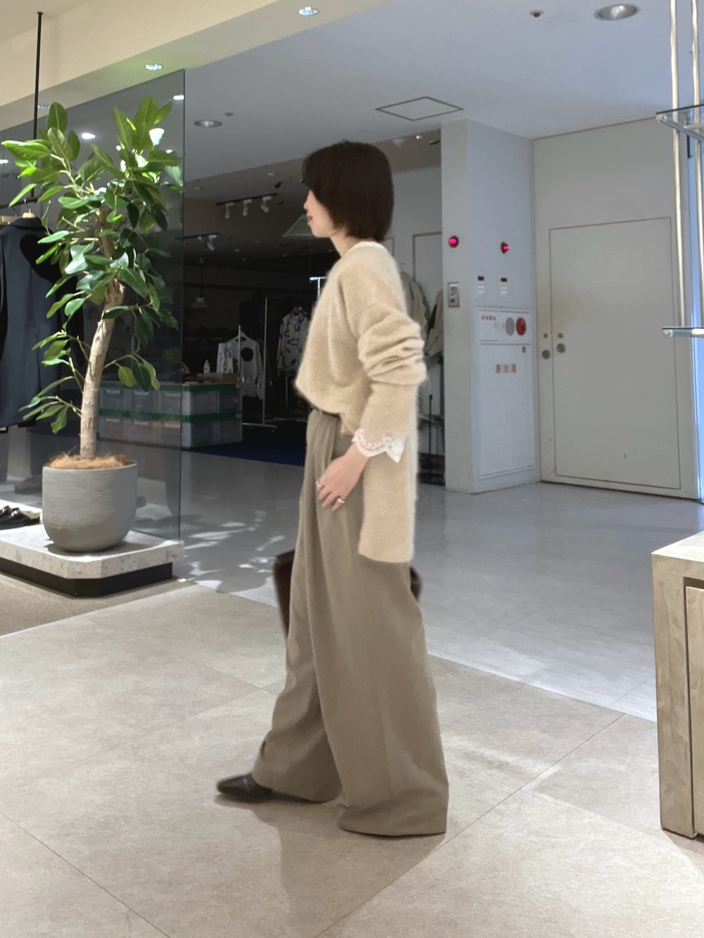 ベージュ系のスラックス、ブラウン系のトートバッグ、ブラウン系のブーツを着用したレディースの秋コーディネートの2枚目の写真
