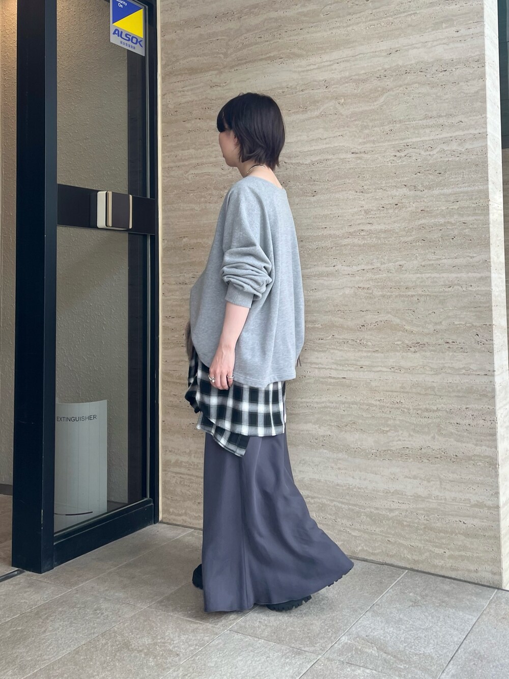 グレー系のスウェット、グレー系のスカート、ブラウン系のハンドバッグを着用したレディースの夏コーディネートの2枚目の写真