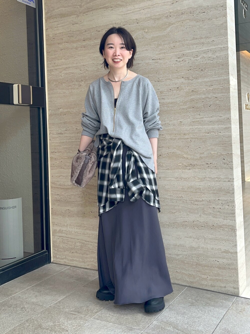 グレー系のスウェット、グレー系のスカート、ブラウン系のハンドバッグを着用したレディースの夏コーディネートの4枚目の写真