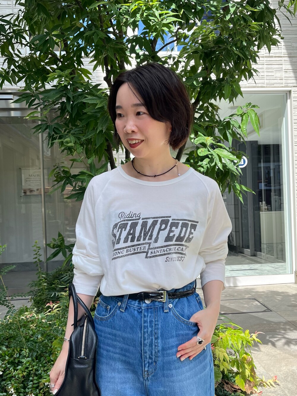 ブルー系のデニムパンツ、ホワイト系のTシャツ/カットソー、ブラック系のボストンバッグを着用したレディースの秋コーディネートの6枚目の写真