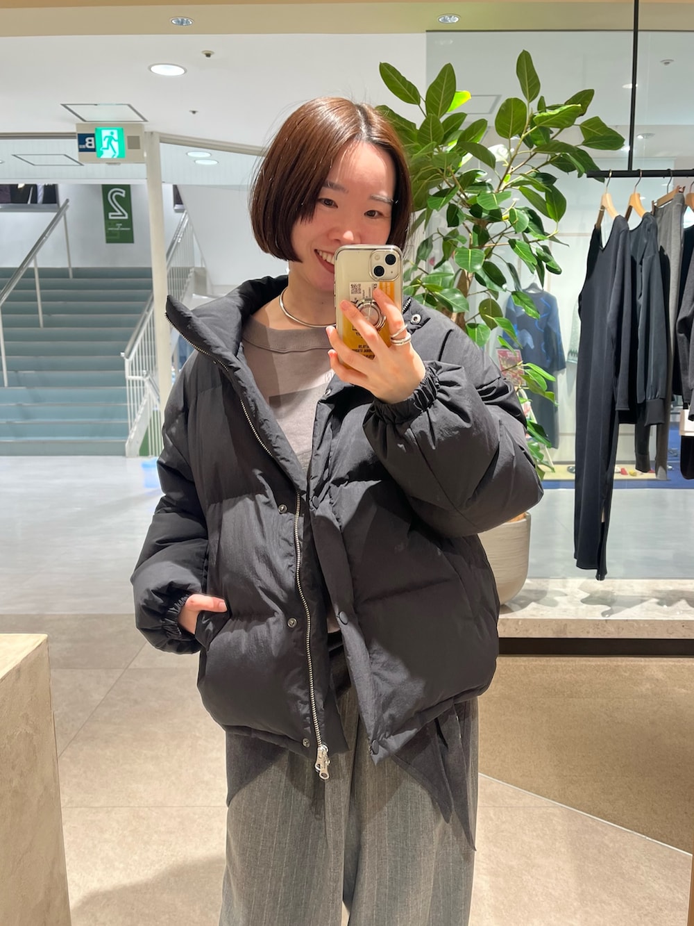 ブラック系のダウンジャケット/コート、グレー系のTシャツ/カットソー、グレー系のスラックスを着用したレディースの冬コーディネートの2枚目の写真