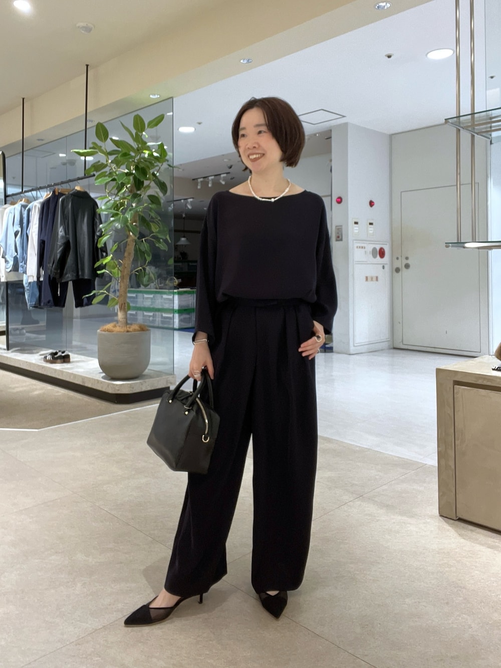 グレー系のテーラードジャケット、ブルー系のスラックス、ブラック系のボストンバッグを着用したレディースの冬コーディネートの7枚目の写真