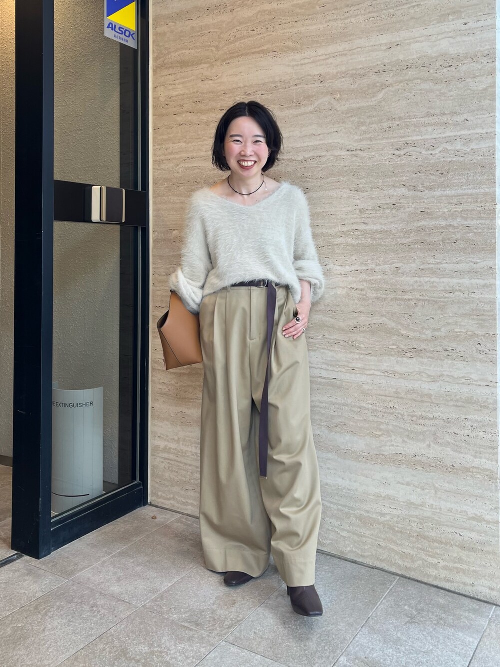 ホワイト系のニット/セーター、ベージュ系のチノパンツ、イエロー系のハンドバッグを着用したレディースの秋コーディネートの4枚目の写真