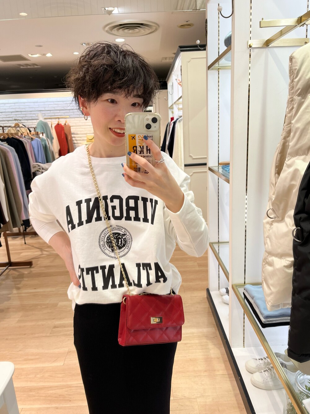 ホワイト系のノーカラーコート、ホワイト系のTシャツ/カットソー、ブラック系のスカートを着用したレディースの冬コーディネートの3枚目の写真