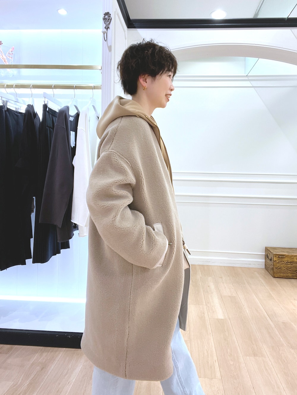 ホワイト系のショルダーバッグ、ベージュ系のノーカラーコート、イエロー系のパーカーを着用したレディースの冬コーディネートの3枚目の写真