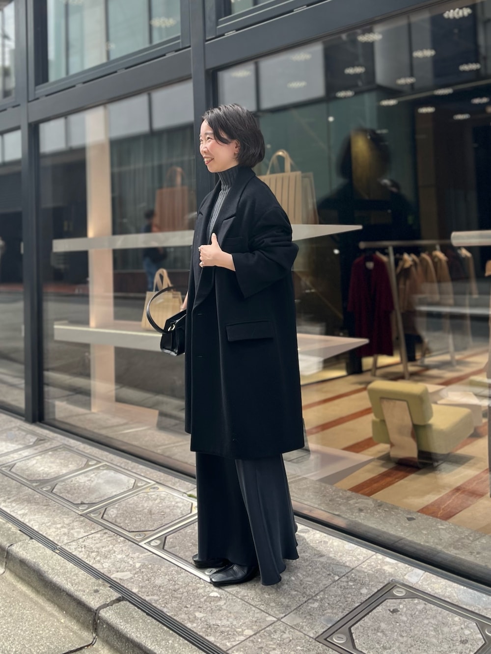 ブラック系のスカート、ブラック系のハンドバッグ、ブラック系のその他アウターを着用したレディースの秋コーディネートの3枚目の写真