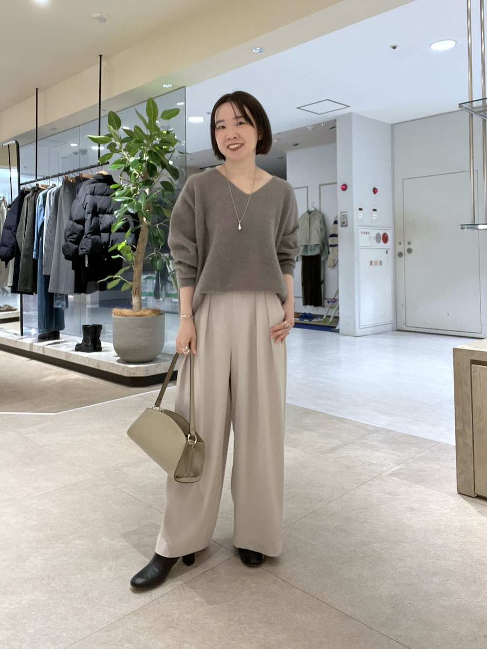 グレー系のニット/セーター、グレー系のスラックス、ベージュ系のハンドバッグを着用したレディースの冬コーディネートの3枚目の写真