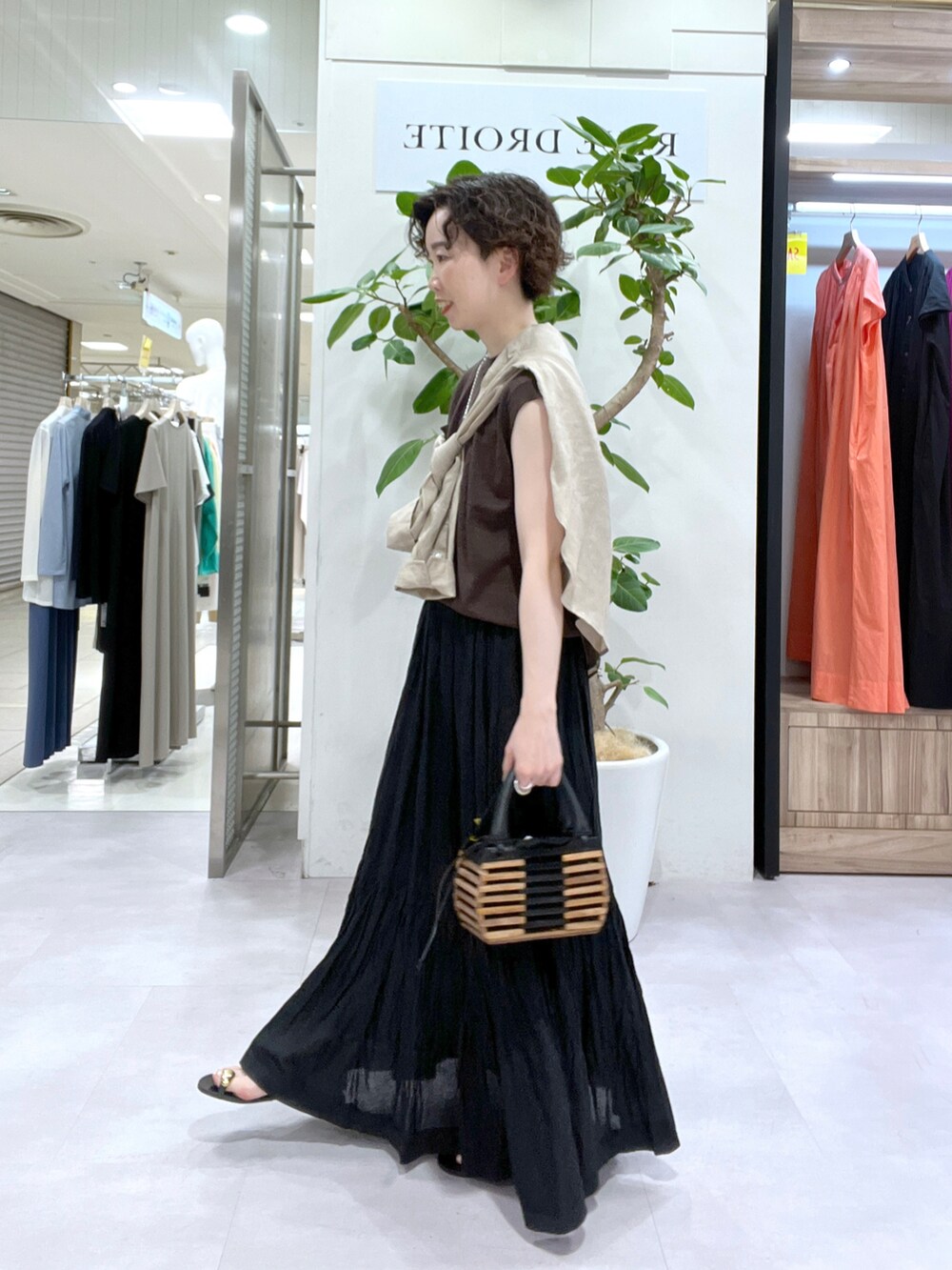 ブラック系のスカート、ベージュ系のシャツ/ブラウス、ブラウン系のニット/セーターを着用したレディースの夏コーディネートの2枚目の写真