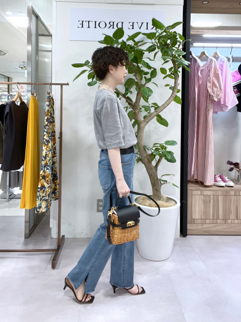 ブラック系のかごバッグ、グレー系のTシャツ/カットソー、ブルー系のデニムパンツを着用したレディースの春コーディネートの2枚目の写真