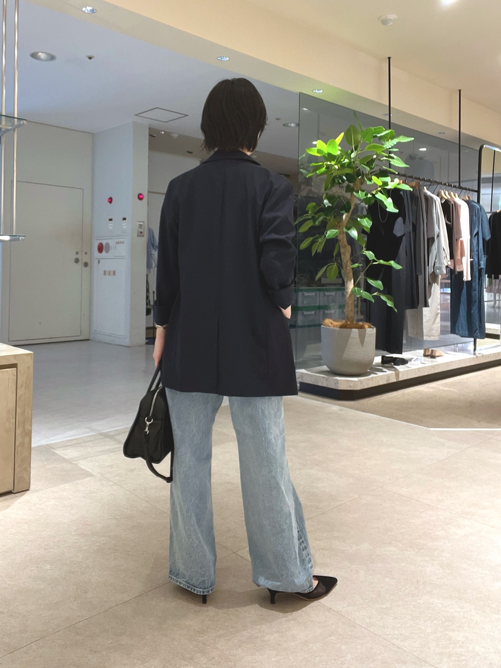 ブルー系のデニムパンツ、ブラック系のパンプス、ブラック系のボストンバッグを着用したレディースの夏コーディネートの3枚目の写真