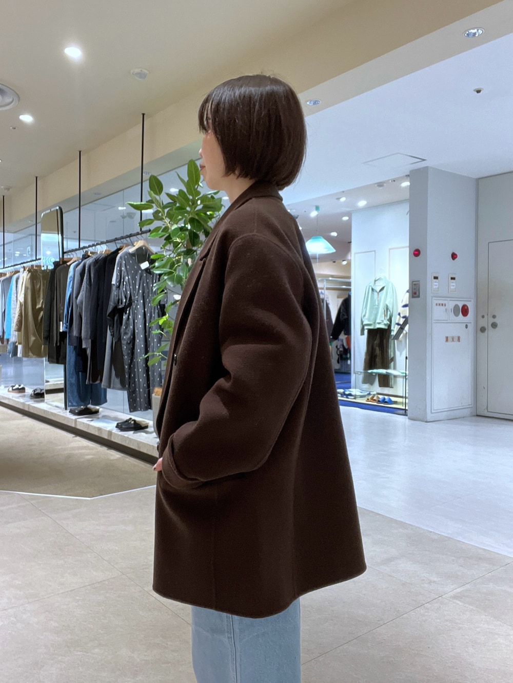 ブルー系のデニムパンツ、ブラウン系のボストンバッグ、ブラウン系のブーツを着用したレディースの秋コーディネートの5枚目の写真