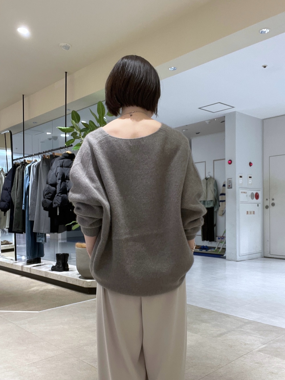 グレー系のニット/セーター、グレー系のスラックス、ベージュ系のハンドバッグを着用したレディースの冬コーディネートの6枚目の写真