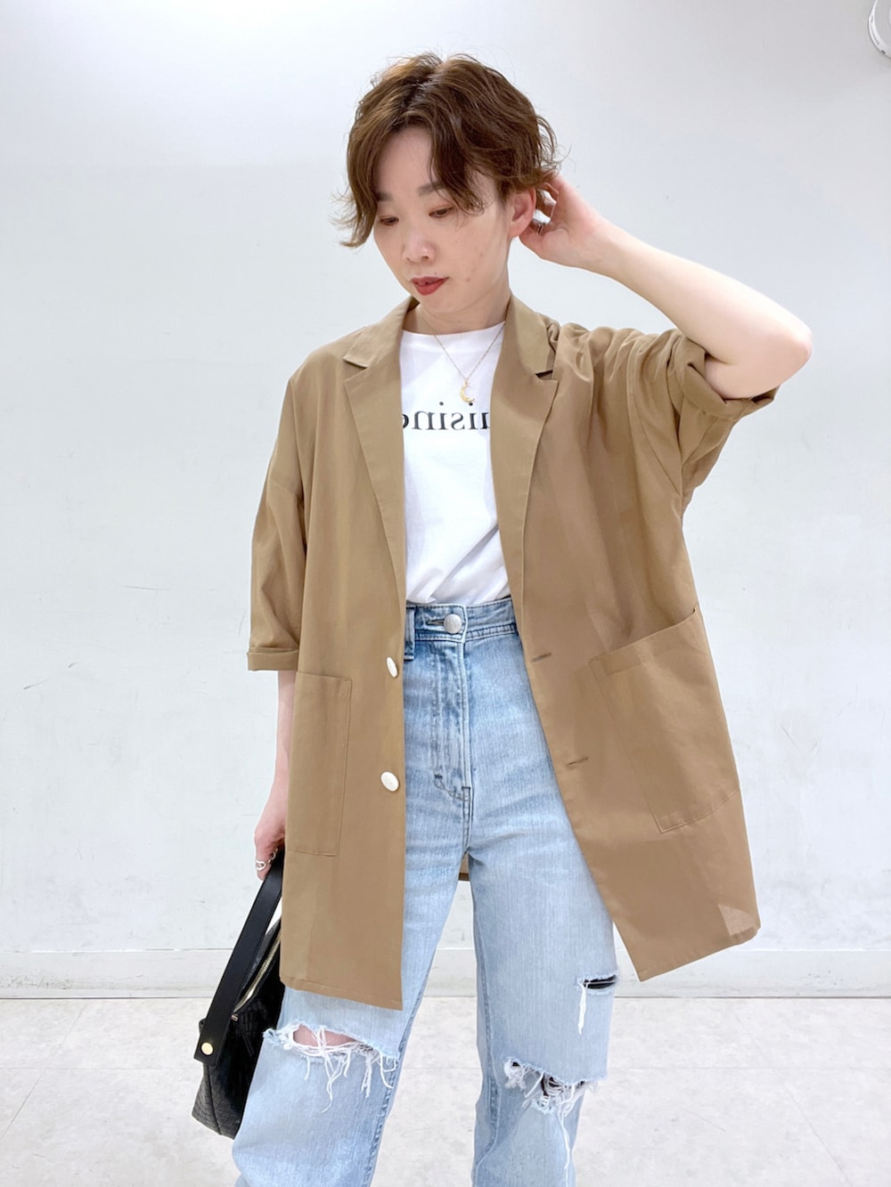 ブルー系のデニムパンツ、ベージュ系のテーラードジャケット、ホワイト系のTシャツ/カットソーを着用したレディースの春コーディネートの2枚目の写真