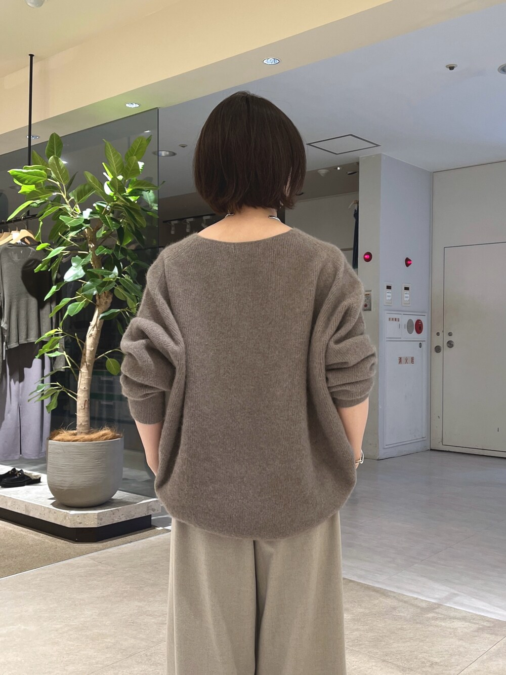 グレー系のニット/セーター、ベージュ系のスラックス、ブラウン系のボストンバッグを着用したレディースの秋コーディネートの7枚目の写真