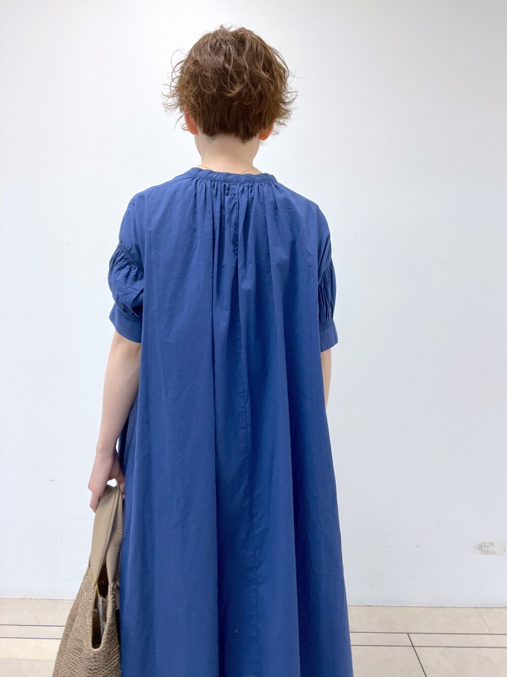 ブルー系のワンピース、グレー系のかごバッグ、ベージュ系のサンダルを着用したレディースの春コーディネートの3枚目の写真