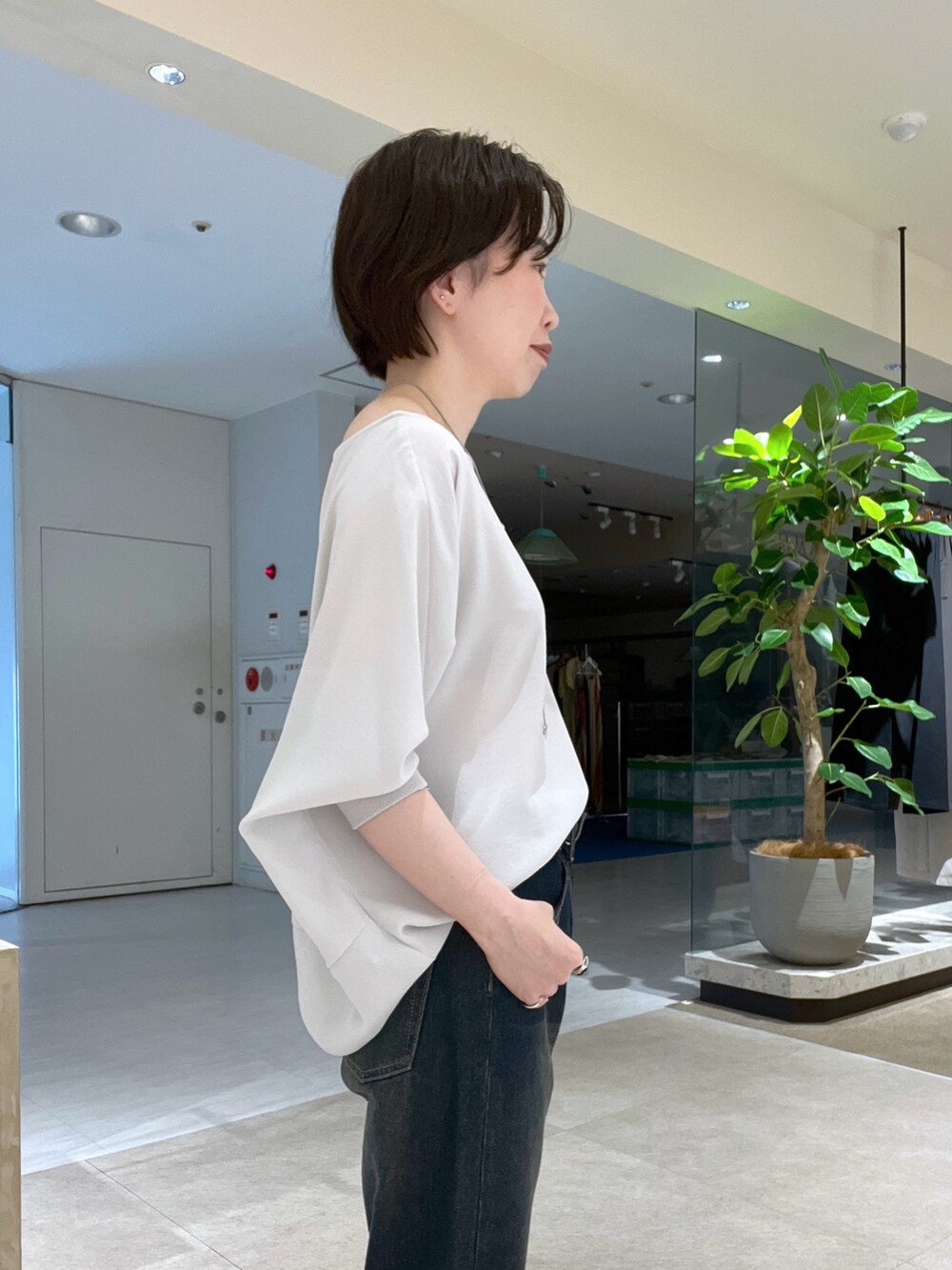 ブルー系のデニムパンツ、ブラック系のハンドバッグ、ブラック系のサンダルを着用したレディースの夏コーディネートの5枚目の写真