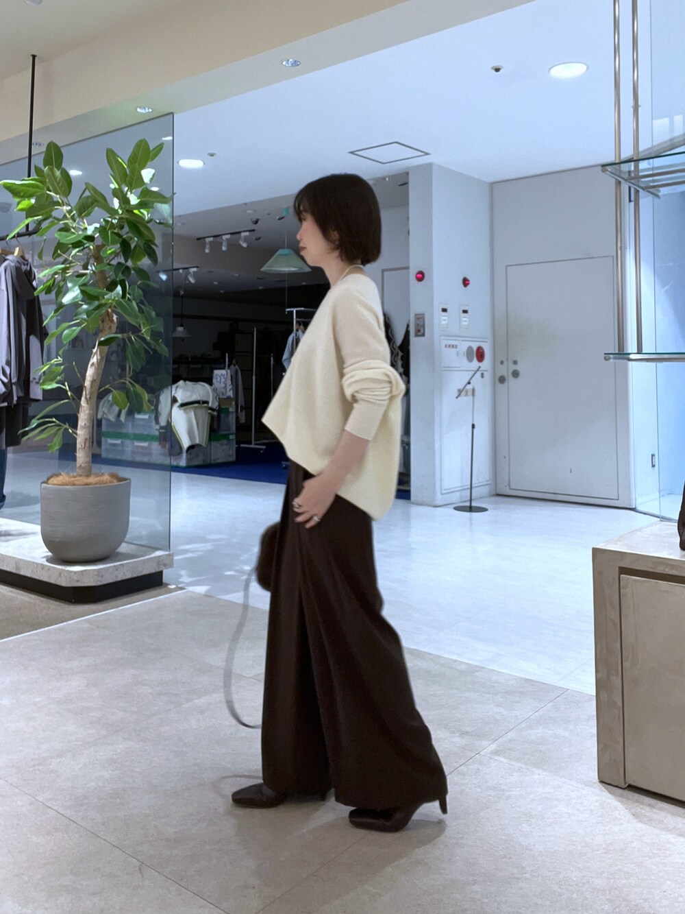 イエロー系のその他アウター、ホワイト系のニット/セーター、ブラウン系のスラックスを着用したレディースの秋コーディネートの6枚目の写真