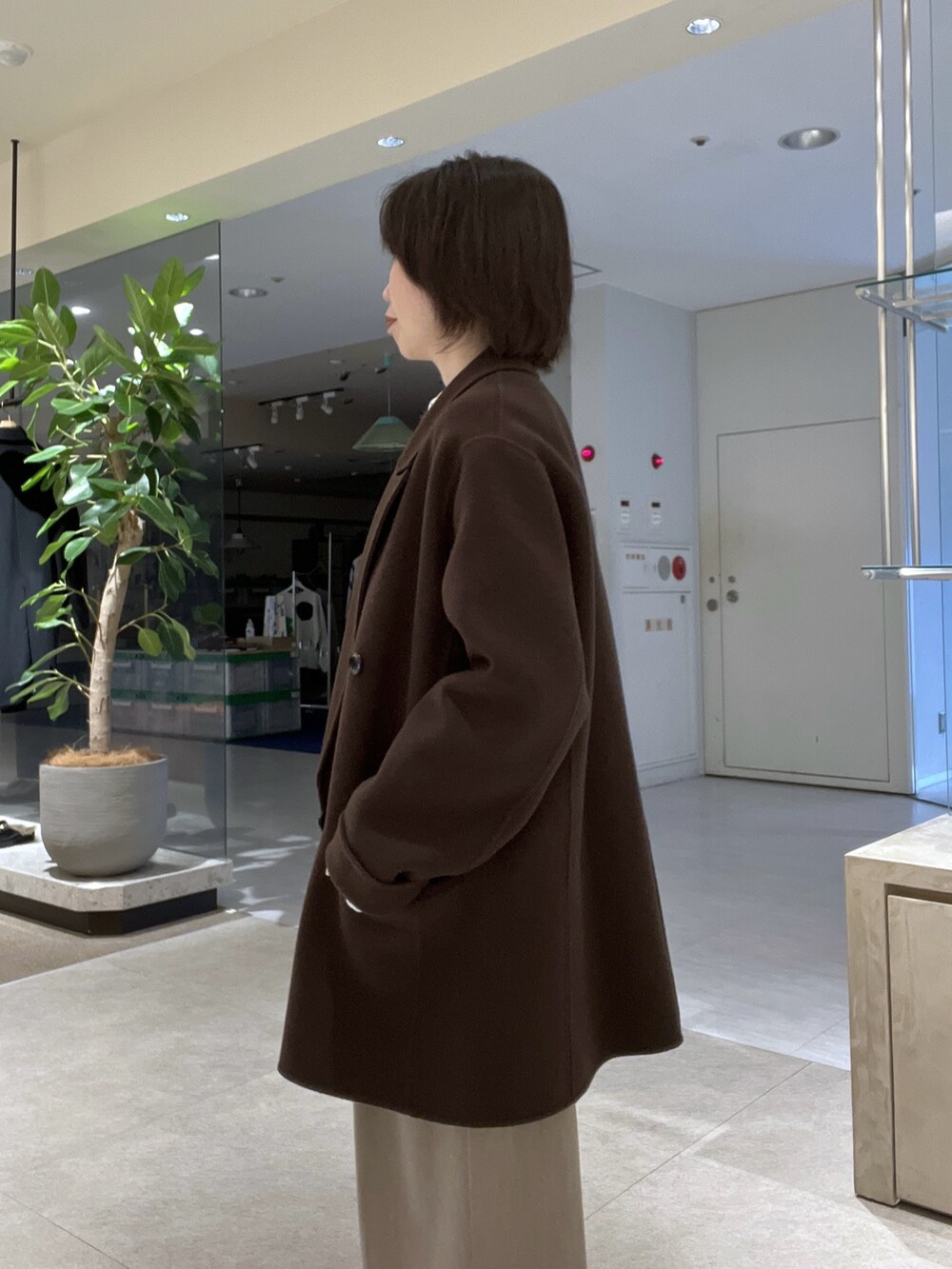 ブラウン系のトートバッグ、ベージュ系のスラックス、ブラウン系のブーツを着用したレディースの秋コーディネートの5枚目の写真