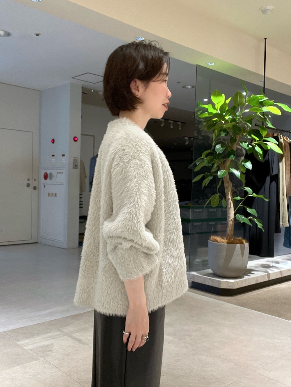 ベージュ系のカーディガン/ボレロ、ブラック系のスカート、ホワイト系のTシャツ/カットソーを着用したレディースの秋コーディネートの5枚目の写真