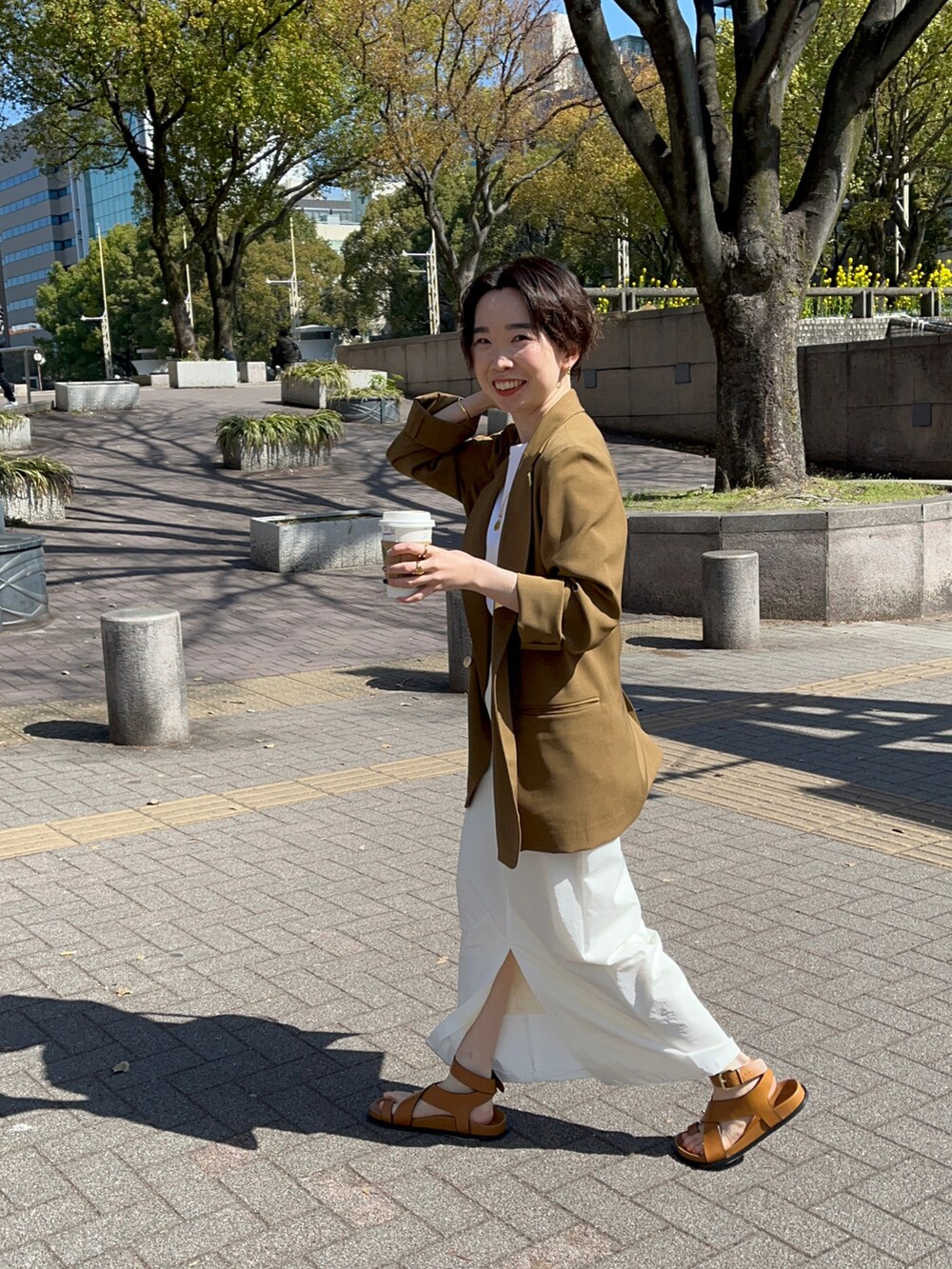 ブラウン系のテーラードジャケット、ホワイト系のTシャツ/カットソー、ホワイト系のスカートを着用したレディースの春コーディネートの3枚目の写真