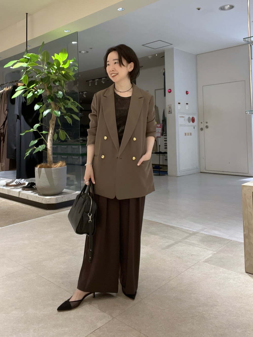 ブラウン系のスラックス、ブラック系のパンプス、ブラウン系のTシャツ/カットソーを着用したレディースの秋コーディネートの2枚目の写真