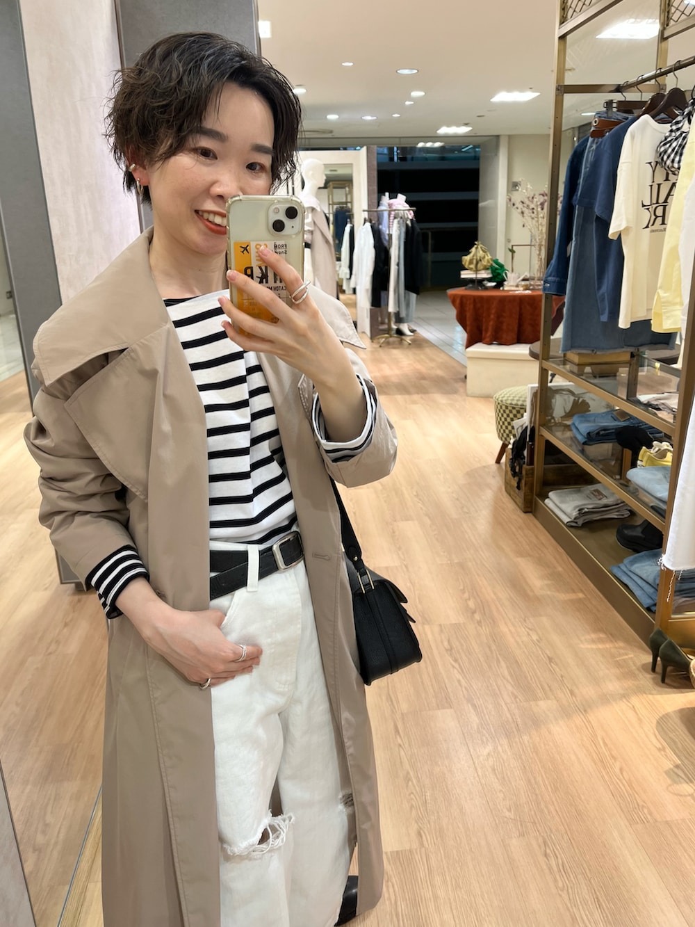 ホワイト系のデニムパンツ、ベージュ系のトレンチコート、ブラック系のTシャツ/カットソーを着用したレディースの冬コーディネートの2枚目の写真