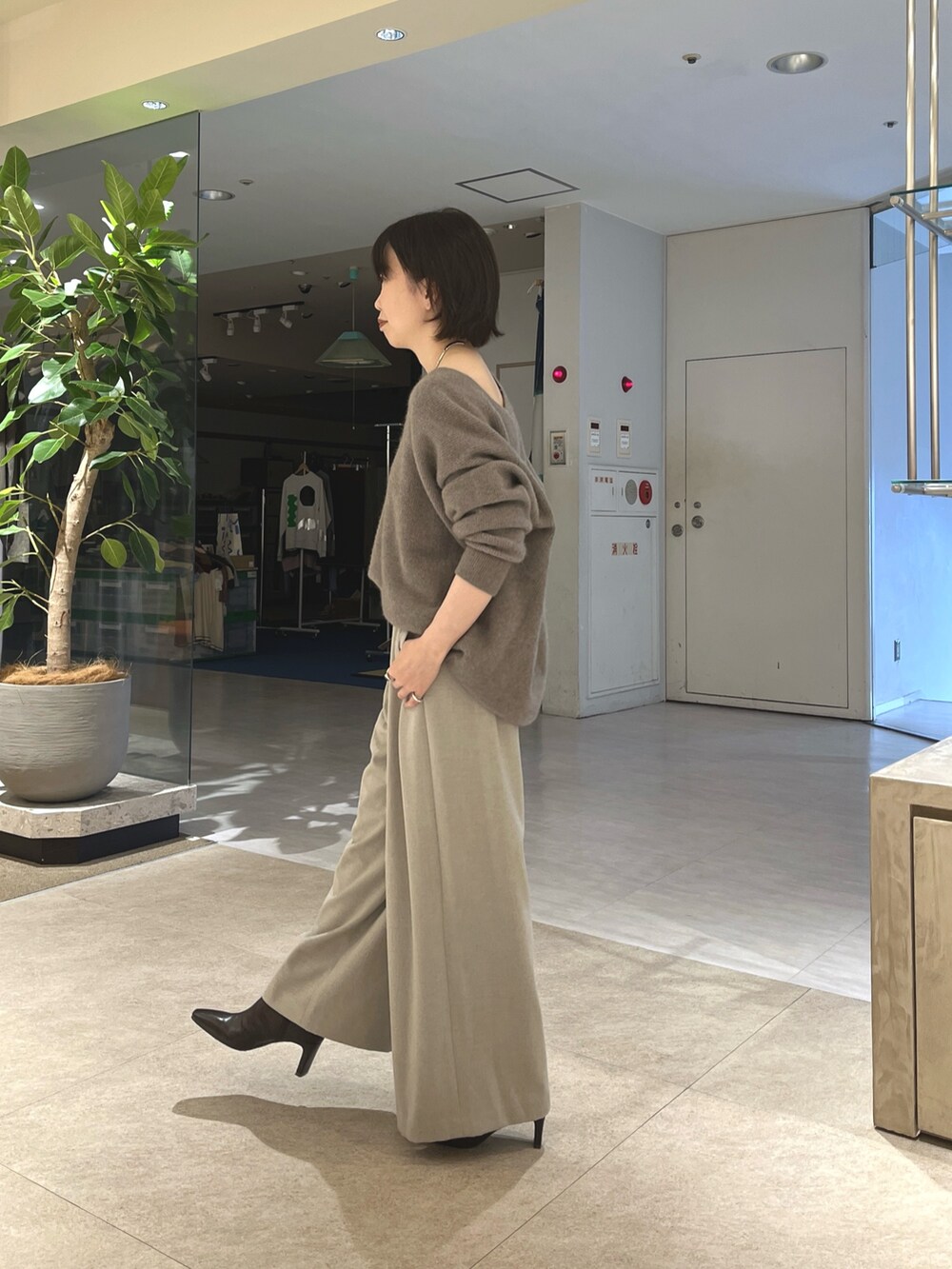 グレー系のニット/セーター、ベージュ系のスラックス、ブラウン系のボストンバッグを着用したレディースの秋コーディネートの5枚目の写真