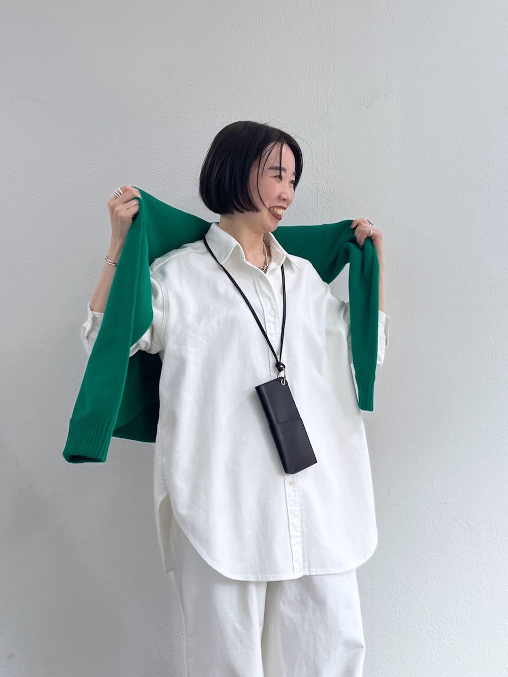 ホワイト系のシャツ/ブラウス、グリーン系のニット/セーター、ホワイト系のデニムパンツを着用したレディースの冬コーディネートの4枚目の写真