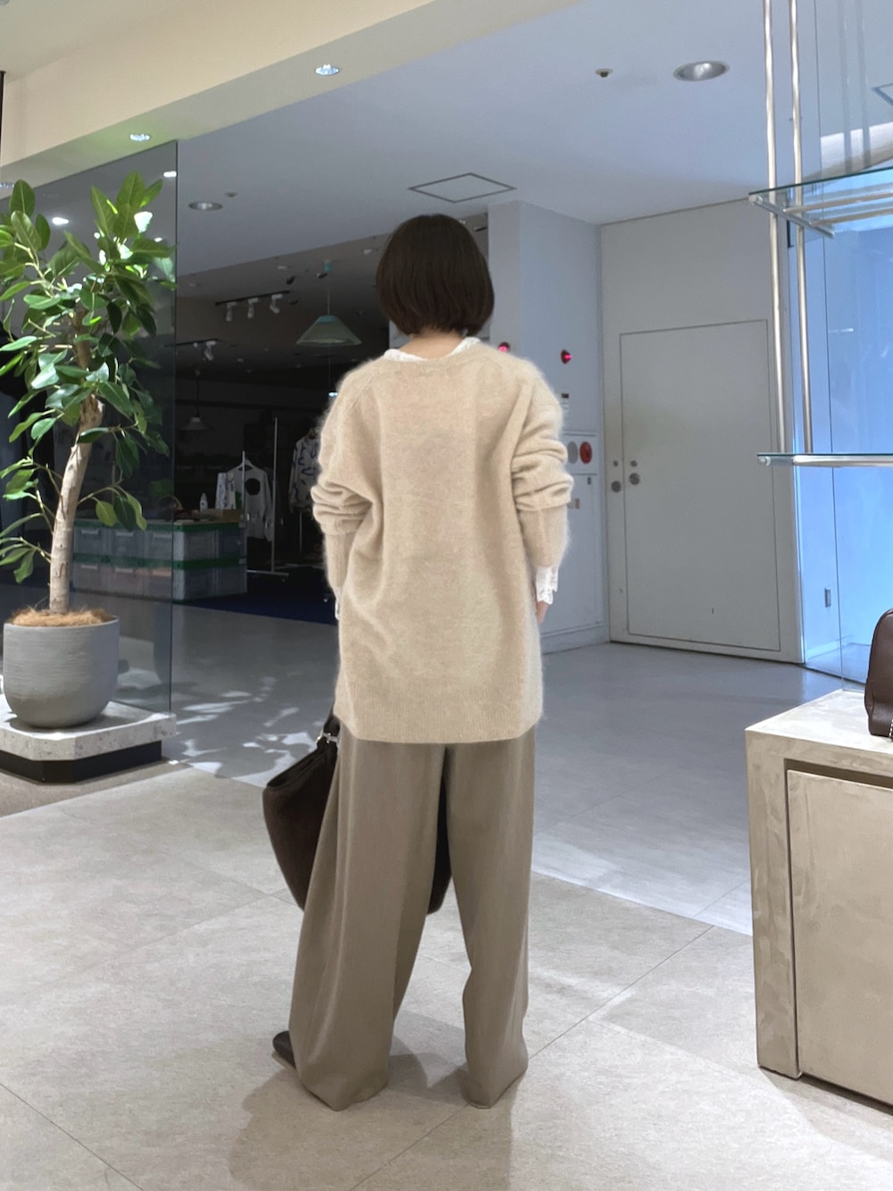 ベージュ系のスラックス、ブラウン系のトートバッグ、ブラウン系のブーツを着用したレディースの秋コーディネートの3枚目の写真