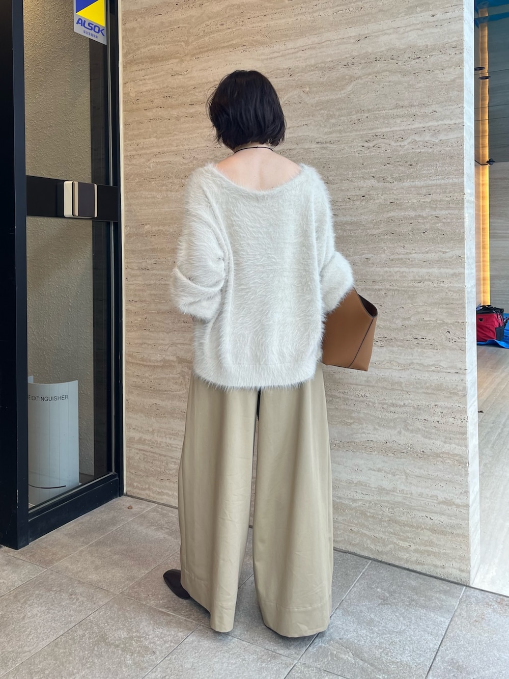 ホワイト系のニット/セーター、ベージュ系のチノパンツ、イエロー系のハンドバッグを着用したレディースの秋コーディネートの3枚目の写真