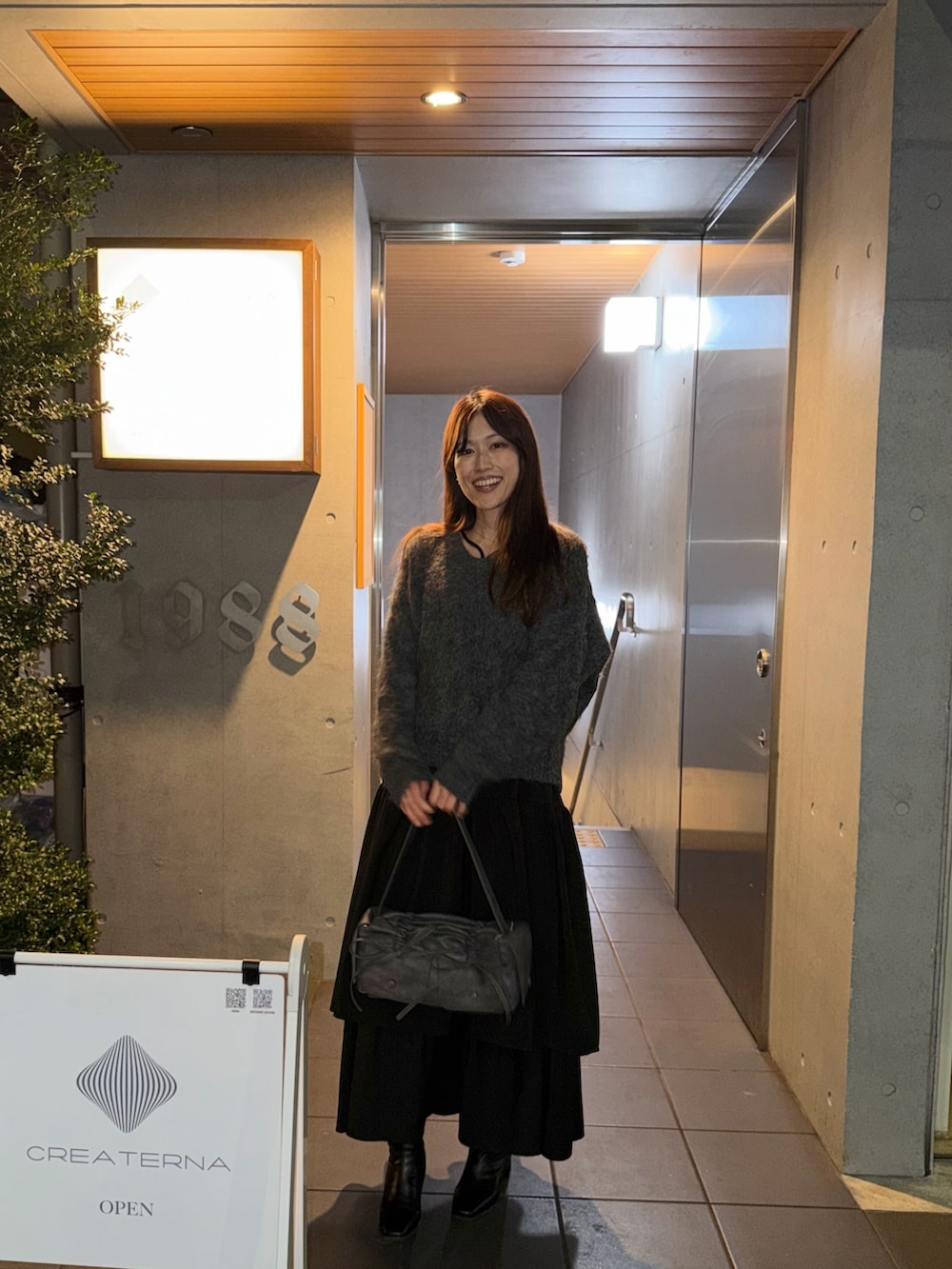 グレー系のトップス、グレー系のバッグ、ブラック系のワンピース/ドレスを着用したレディースの冬コーディネートの4枚目の写真