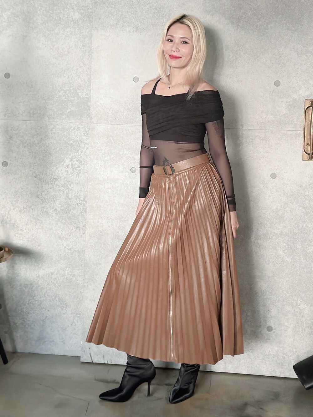 ブラウン系のスカート、ブラック系のブーティを着用したレディースの秋コーディネートの2枚目の写真