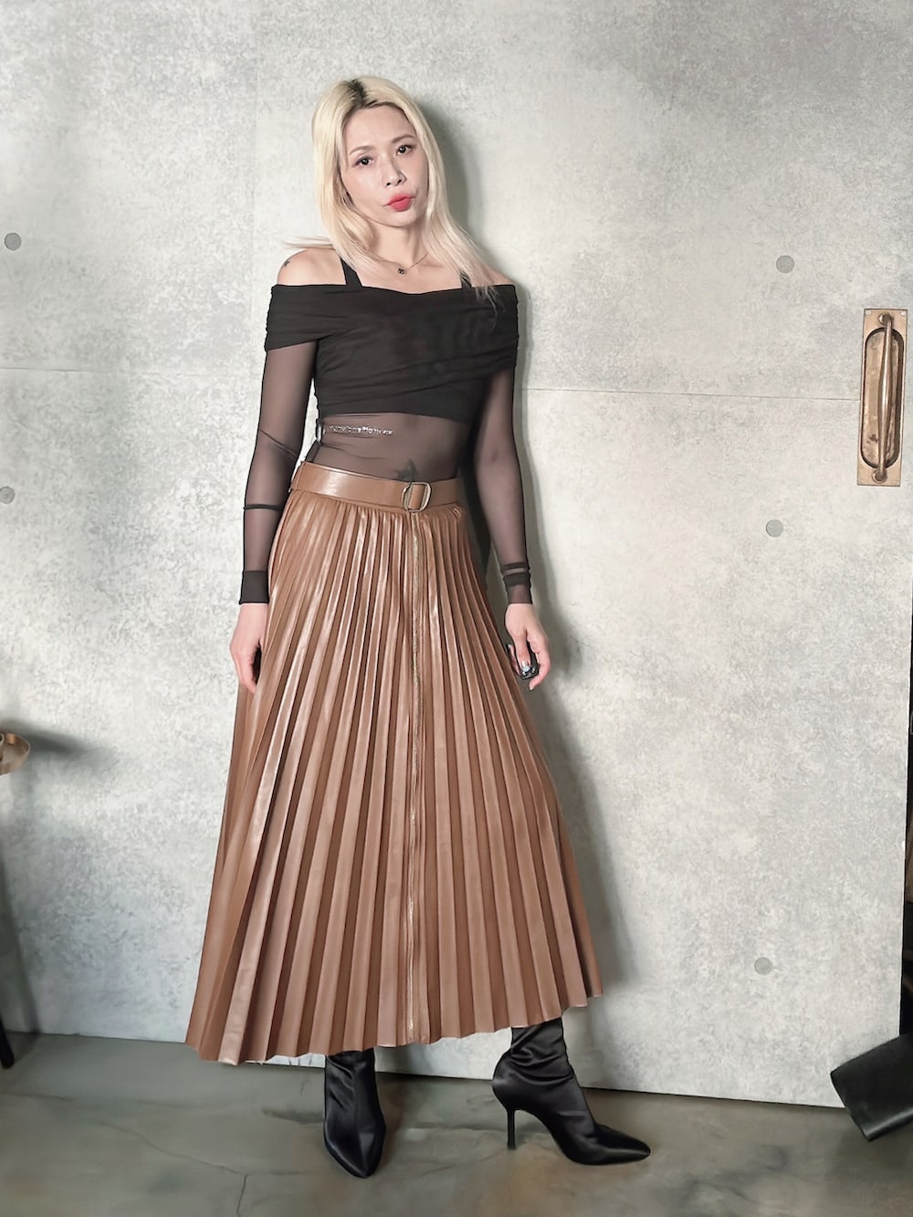 ブラウン系のスカート、ブラック系のブーティを着用したレディースの秋コーディネートの3枚目の写真