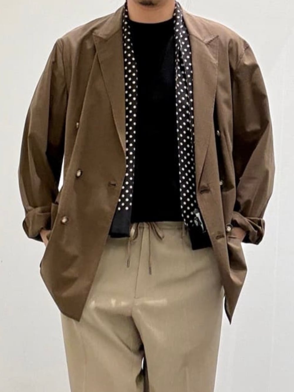 ブラウン系のテーラードジャケット、ブラック系のTシャツ/カットソー、ベージュ系のスラックスを着用したメンズの夏コーディネートの4枚目の写真