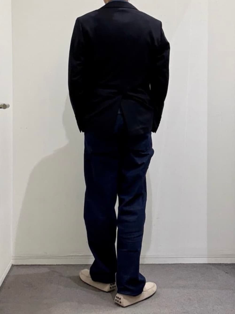 グレー系のスリッポン、ブルー系のテーラードジャケット、ブルー系のデニムパンツを着用したメンズの夏コーディネートの3枚目の写真
