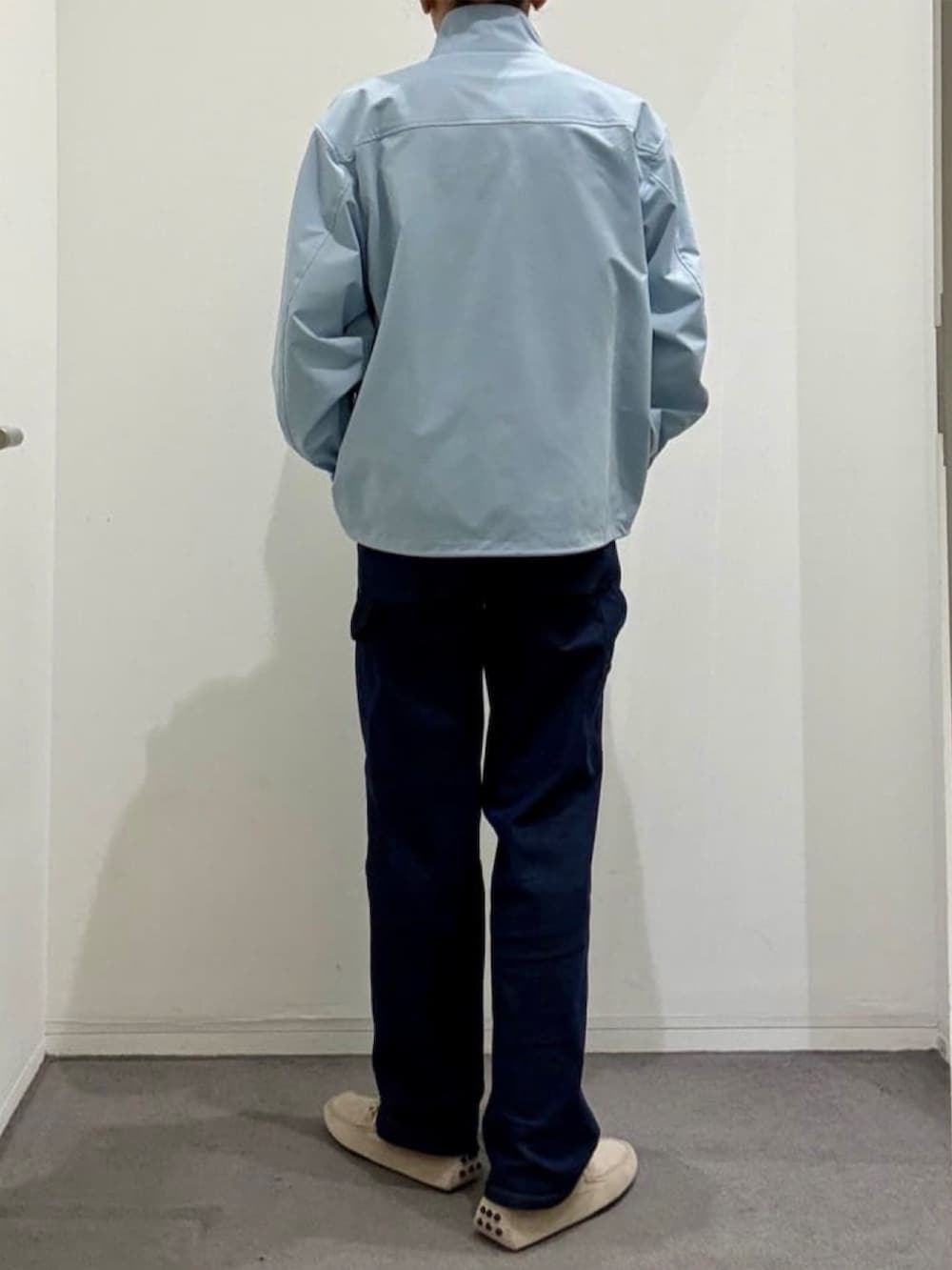 ホワイト系のニット/セーター、グレー系のスリッポン、ブルー系のデニムパンツを着用したメンズの夏コーディネートの3枚目の写真