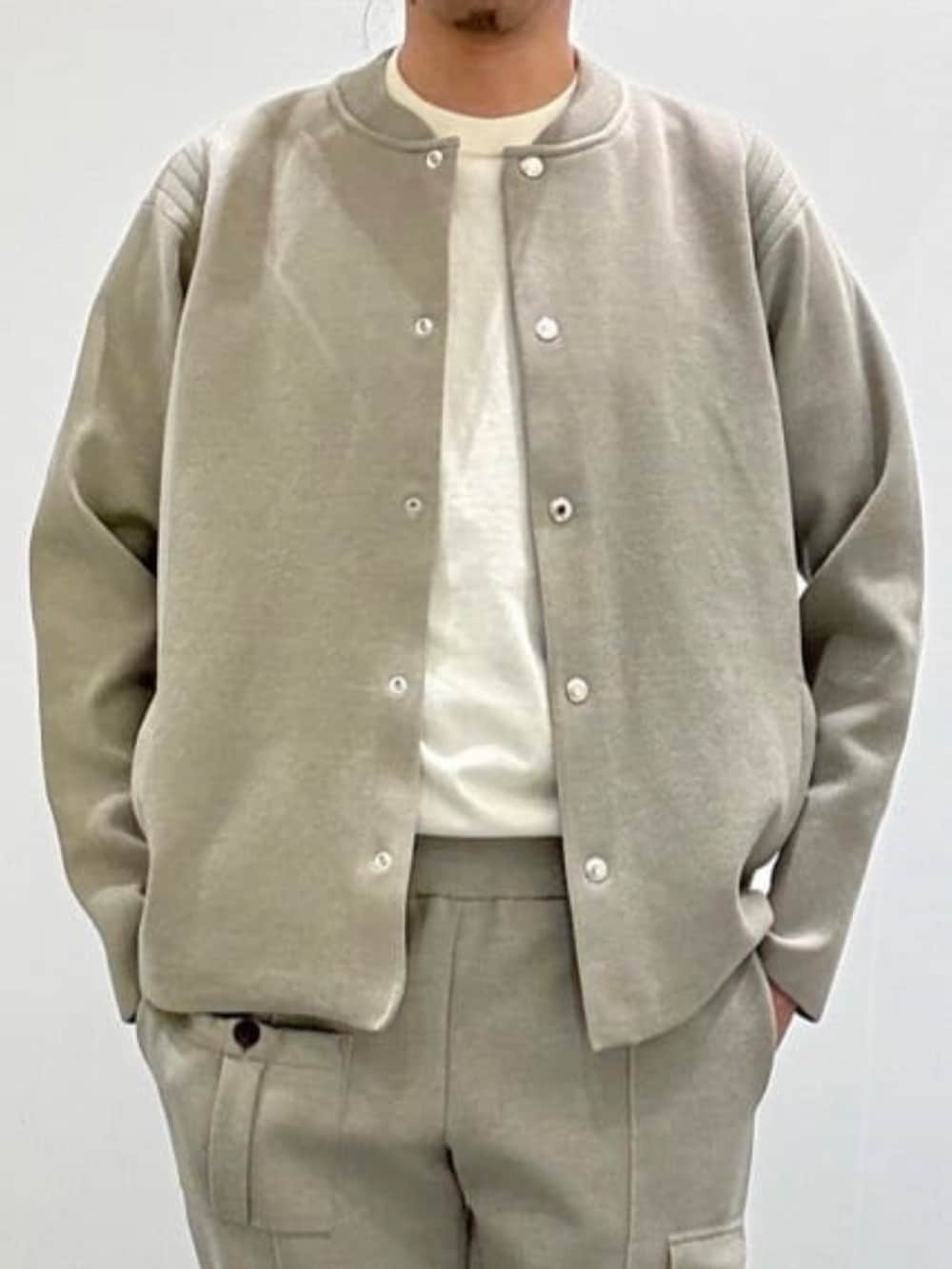 ベージュ系のブルゾン、ホワイト系のニット/セーター、ベージュ系のスラックスを着用したメンズの夏コーディネートの2枚目の写真