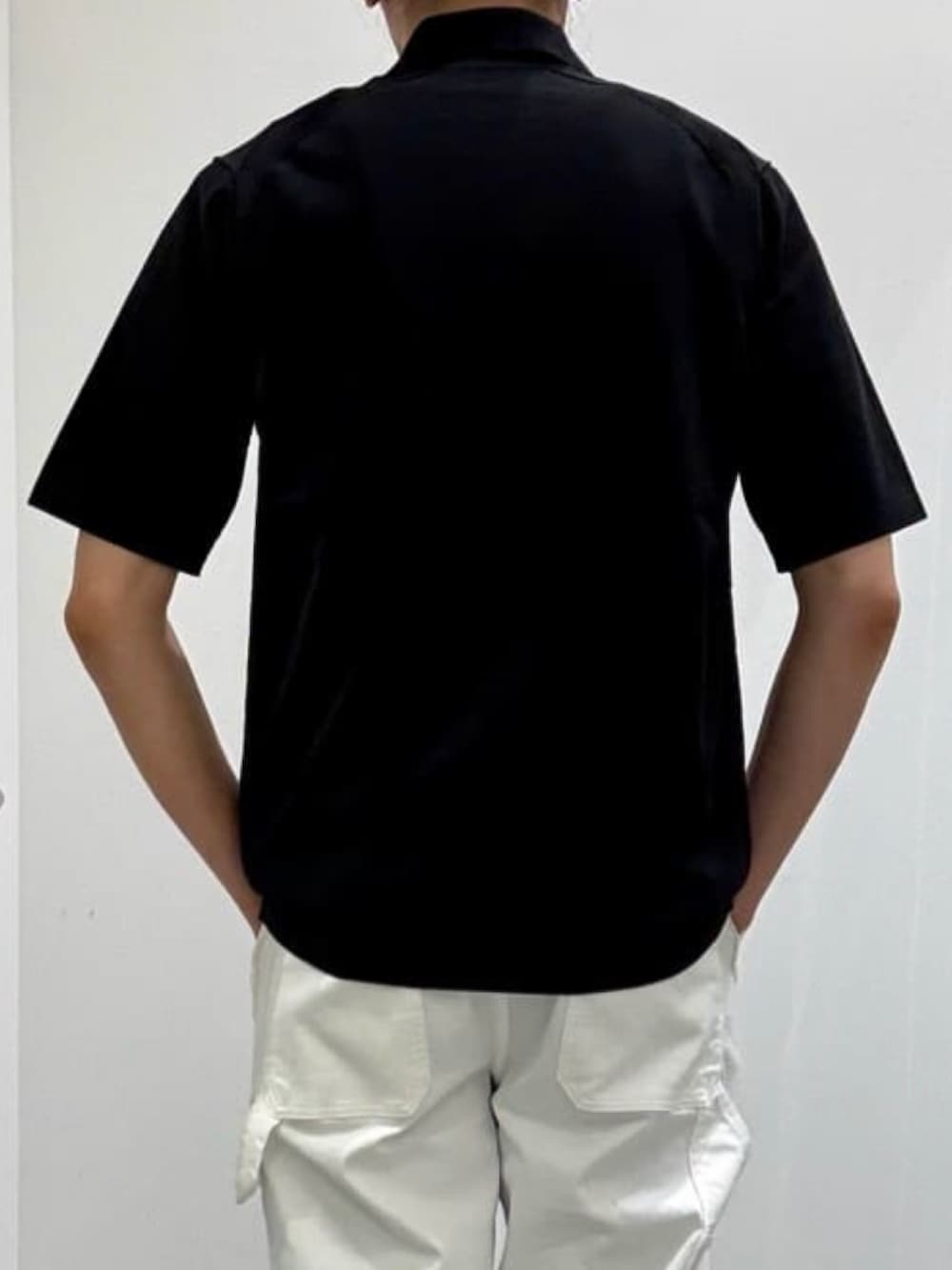 ホワイト系のデニムパンツ、グレー系のショルダーバッグ、ブラック系のポロシャツを着用したメンズの夏コーディネートの6枚目の写真