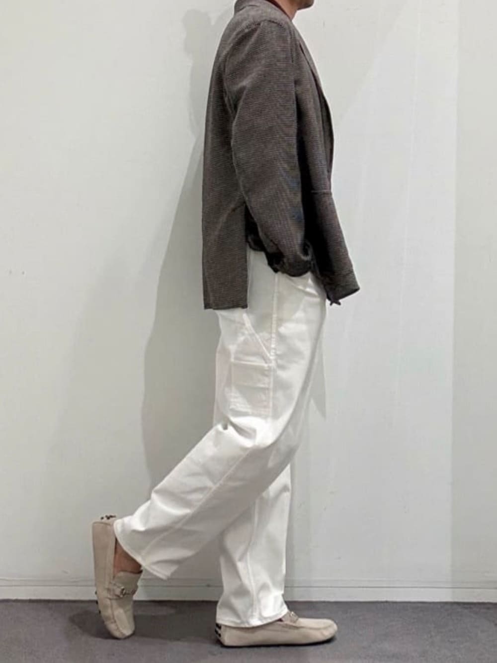 ホワイト系のデニムパンツ、グレー系のスリッポン、ブラウン系のポロシャツを着用したメンズの夏コーディネートの2枚目の写真