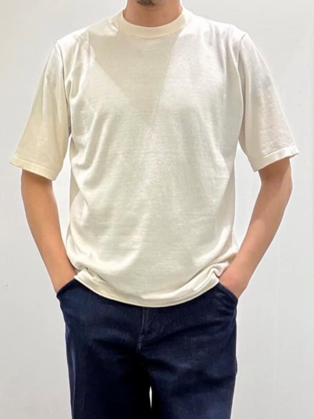 ホワイト系のニット/セーター、グレー系のスリッポン、ブルー系のデニムパンツを着用したメンズの夏コーディネートの8枚目の写真