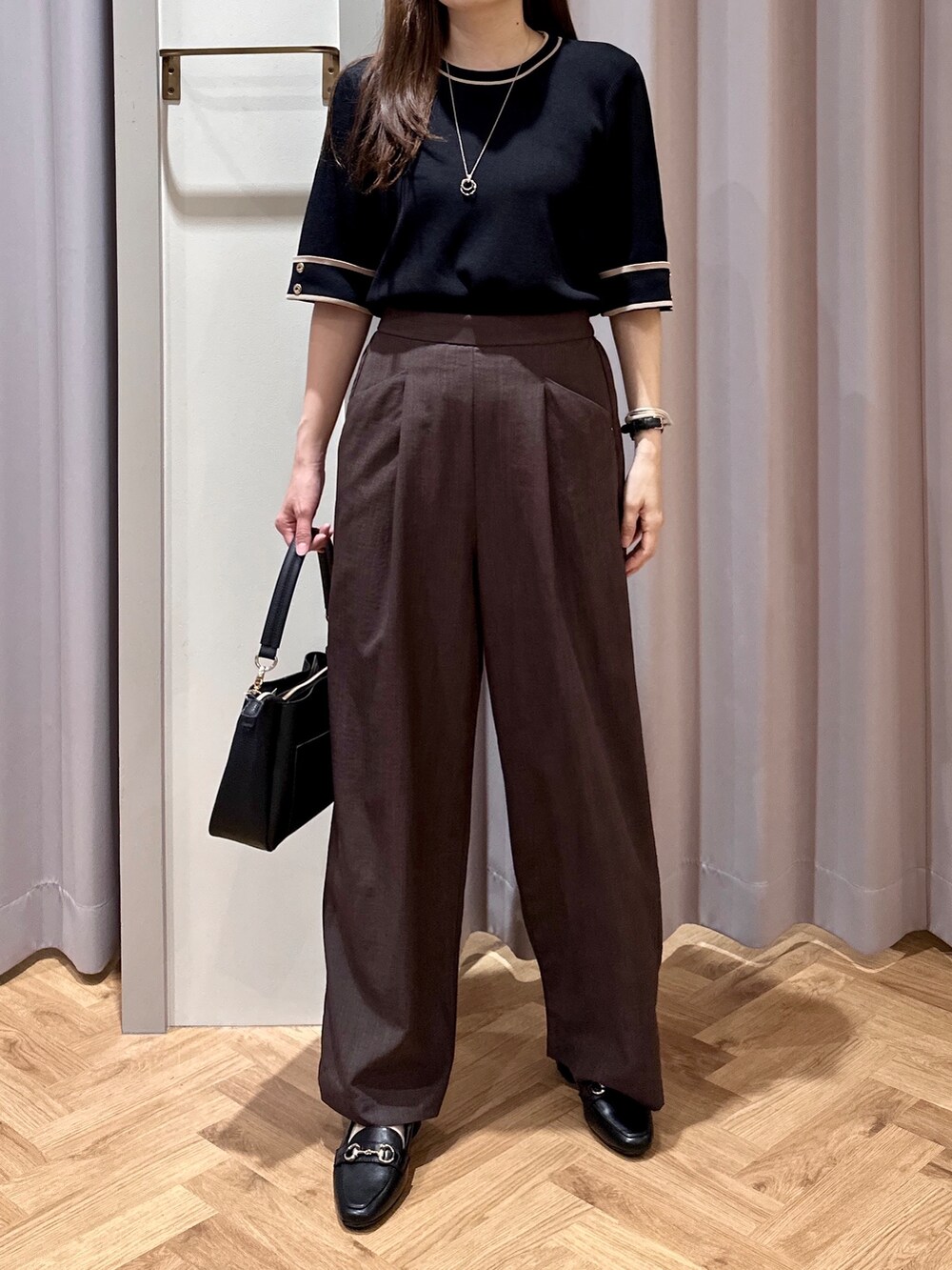 ブラック系のニット/セーター、ブラウン系のその他パンツ、ブラック系のショルダーバッグを着用したレディースの夏コーディネートの4枚目の写真
