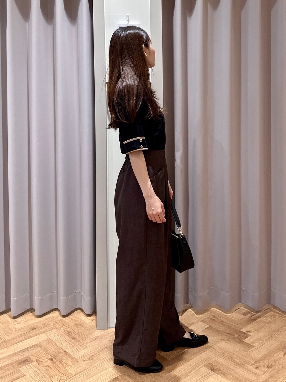 ブラック系のニット/セーター、ブラウン系のその他パンツ、ブラック系のショルダーバッグを着用したレディースの夏コーディネートの2枚目の写真