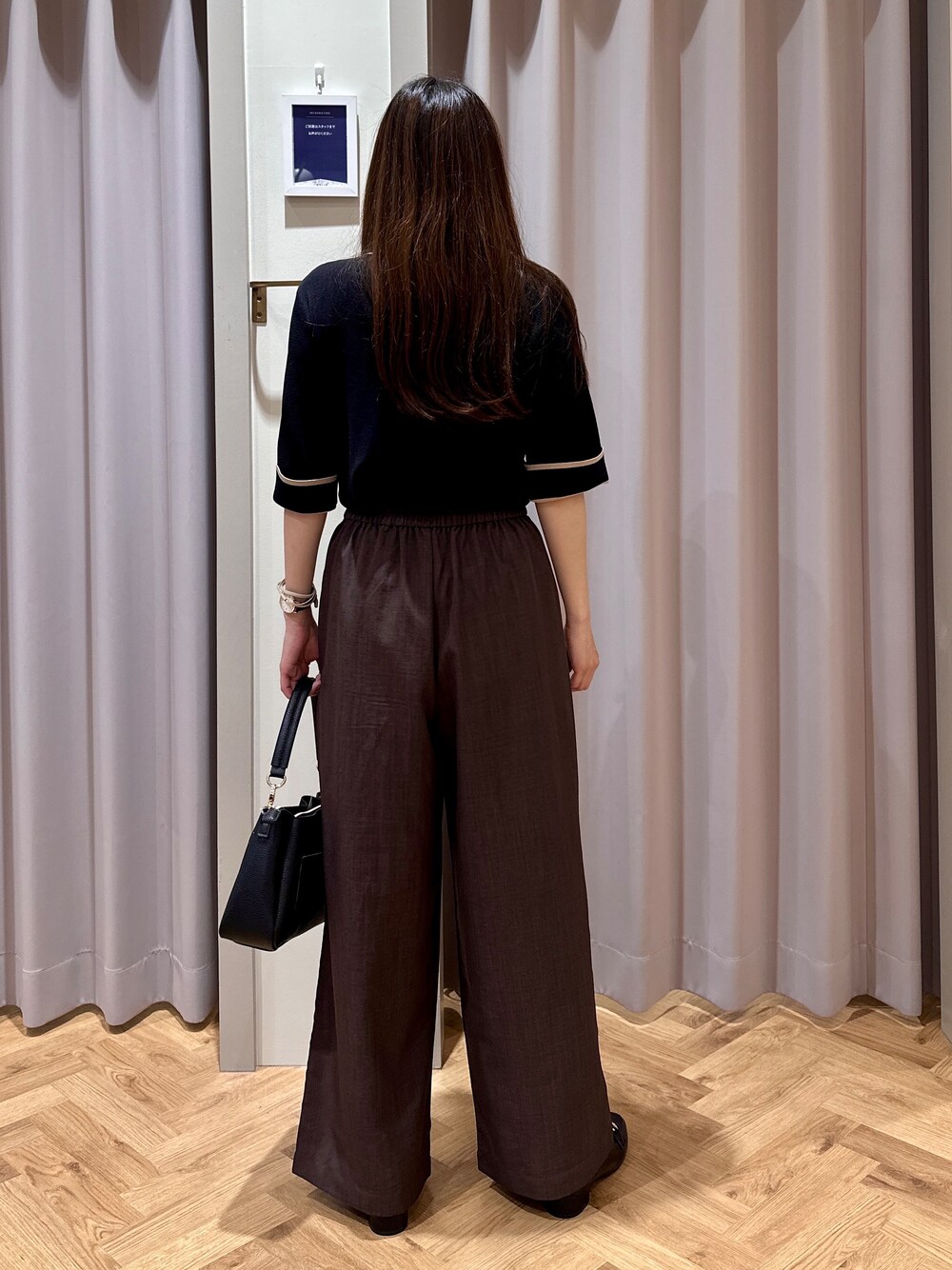 ブラック系のニット/セーター、ブラウン系のその他パンツ、ブラック系のショルダーバッグを着用したレディースの夏コーディネートの3枚目の写真