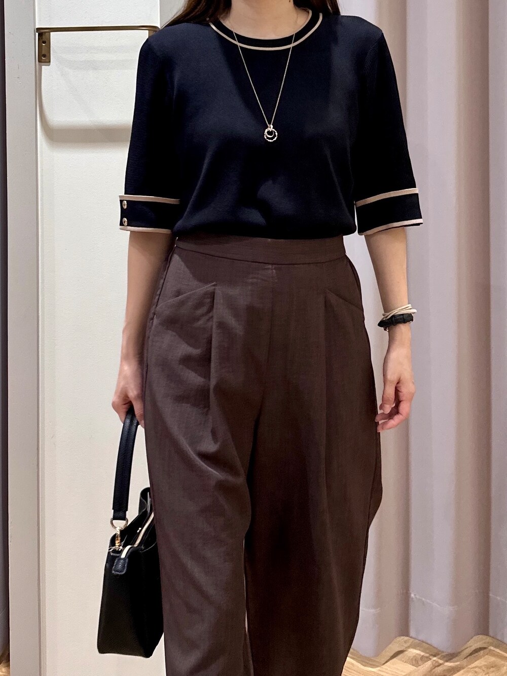 ブラック系のニット/セーター、ブラウン系のその他パンツ、ブラック系のショルダーバッグを着用したレディースの夏コーディネートの7枚目の写真