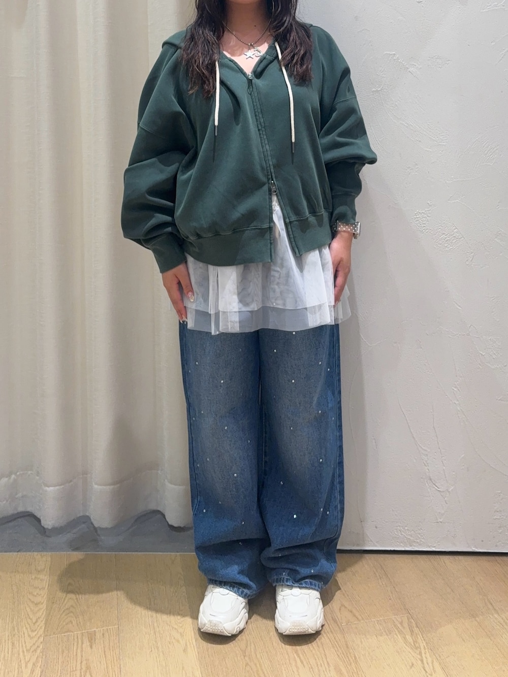 グリーン系のパーカー、ホワイト系のキャミソール、ブルー系のデニムパンツを着用したレディースの秋コーディネートの3枚目の写真