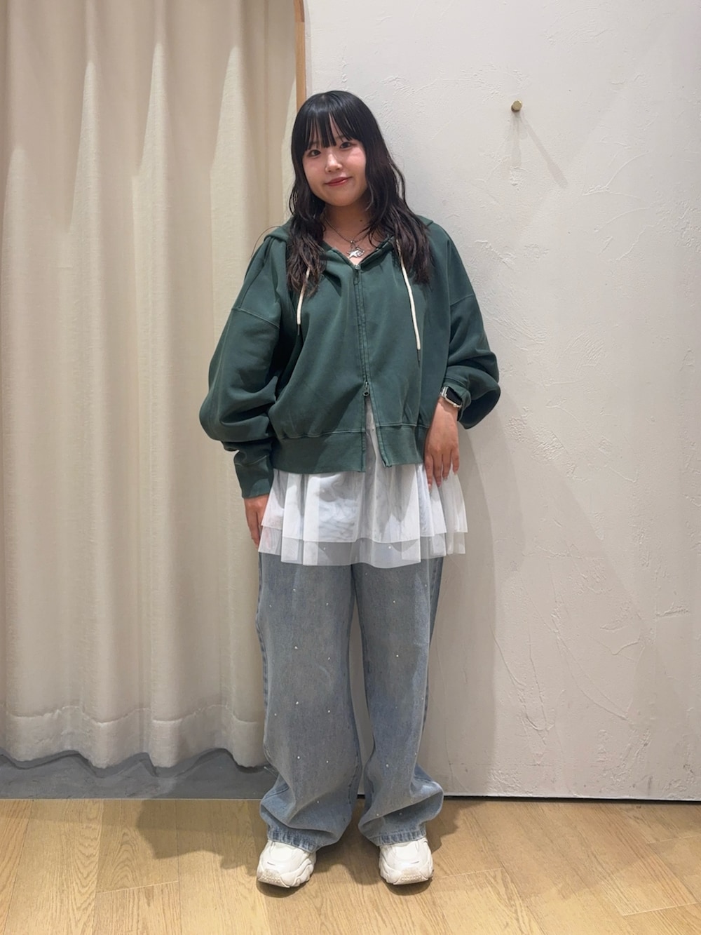 グリーン系のパーカー、ホワイト系のキャミソール、ブルー系のデニムパンツを着用したレディースの秋コーディネートの2枚目の写真