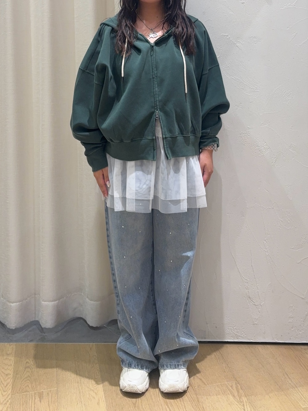 グリーン系のパーカー、ホワイト系のキャミソール、ブルー系のデニムパンツを着用したレディースの秋コーディネートの3枚目の写真