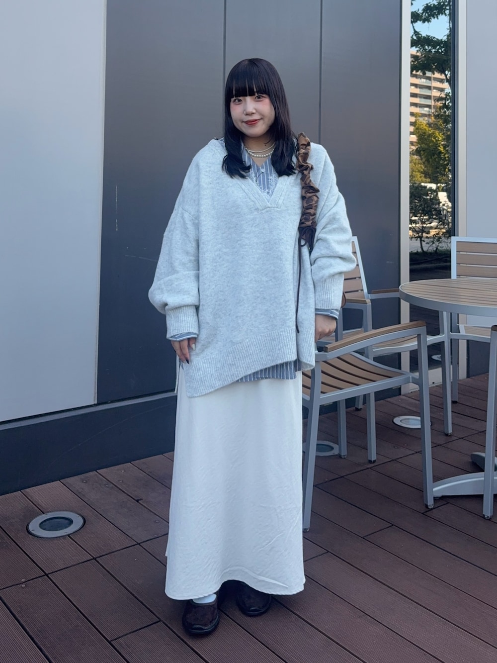 ホワイト系のニット/セーター、ブルー系のシャツ/ブラウス、イエロー系のショルダーバッグを着用したレディースの秋コーディネートの2枚目の写真