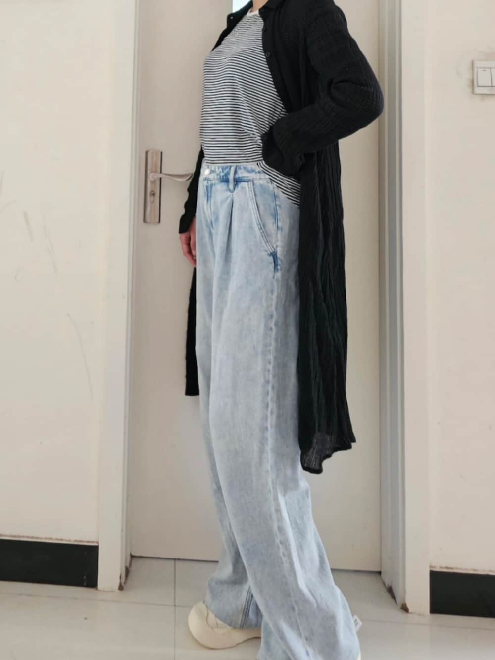 ブラック系のパンプス、ブルー系のデニムパンツ、ブラック系のカーディガン/ボレロを着用したレディースの春コーディネートの2枚目の写真