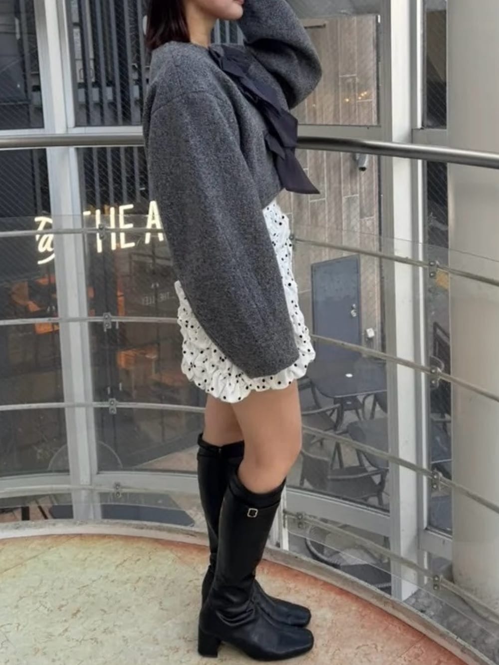 ホワイト系のスカート、グレー系のブルゾン、ブラック系のブーツを着用したレディースの冬コーディネートの5枚目の写真